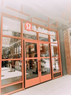 an orange store front with people walking in it