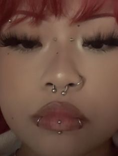 a woman with red hair and piercings on her nose