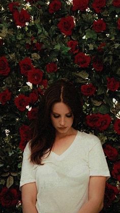 a woman standing in front of a rose covered wall