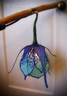 a blue and purple flower hanging from a door handle with a light on it's side