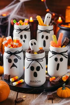 mason jars decorated with candy and candies in the shape of ghost's faces