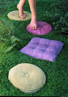 someone standing in the grass with their feet on some pillows and rugs around them