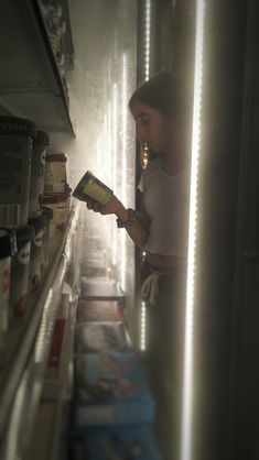 a woman standing in front of a shelf looking at a box with food on it