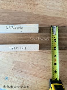 a measuring tape is next to a toy car on a wooden table with rulers