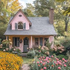 a small pink house surrounded by flowers and trees