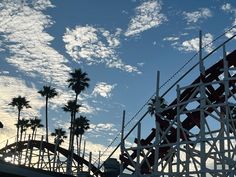 the roller coaster at an amusement park with palm trees and blue sky in the background