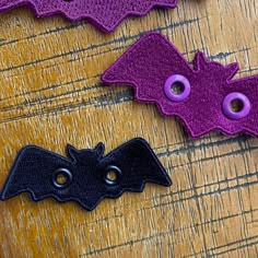 three bat shaped buttons sitting on top of a wooden table