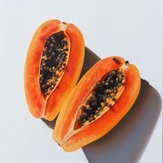 two pieces of papaya sitting on top of a white table next to each other