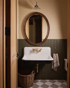 a white sink sitting under a round mirror in a bathroom next to a wooden door