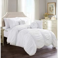 a bed with white comforters and pillows in a room