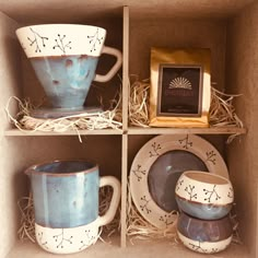 three blue and white coffee cups in a box with two saucers, one cup on the other