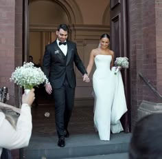 a bride and groom walking down the steps holding hands as they leave their wedding ceremony