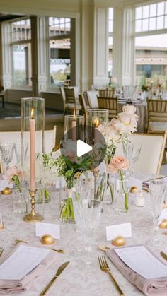 a table set up with place settings and flowers in vases, candles and napkins