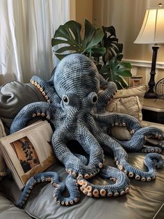 an octopus stuffed animal sitting on top of a bed next to a book and lamp