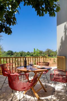 an outdoor table and chairs on a patio with a bottle of wine in the background