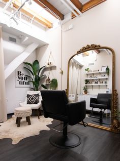 a chair and mirror in a room with wooden floors, white walls and exposed ceilings