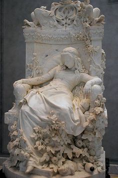 a statue of a woman laying on top of a bed covered in shells and flowers