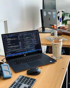 an open laptop computer sitting on top of a wooden desk next to a cup of coffee