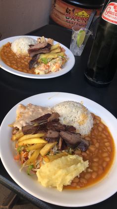 two plates of food are sitting on a table next to a bottle of booze