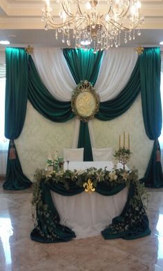 a banquet table set up with green and white drapes, flowers, candles, and decorations