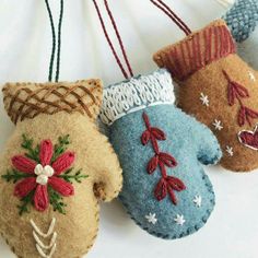 three handmade mittens hanging from strings on a white wall with red and blue decorations