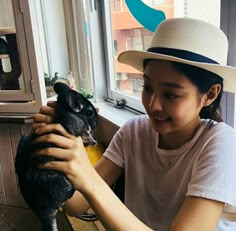 a woman in a hat petting a small animal