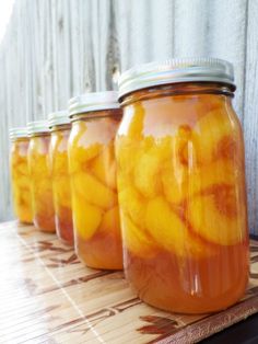 four jars filled with pickles sitting on top of a wooden table