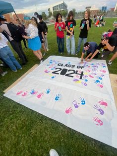 a group of people standing around a large banner with hand prints on it and the words class of 2012 written on it