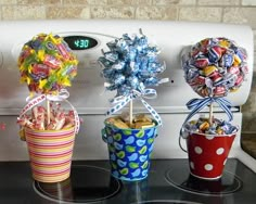 three buckets filled with candy sitting on top of a counter next to an appliance