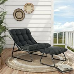 a black chair sitting on top of a wooden floor next to a white wall and potted plant