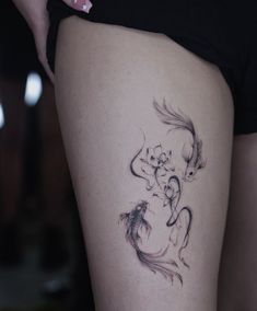 a woman's thigh with a tattoo of a fish and flowers on the side