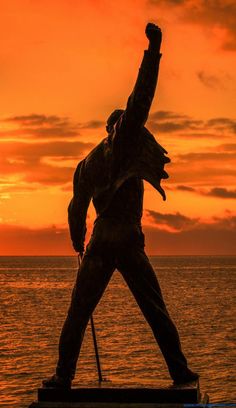 a statue of a man holding a baseball bat in front of an orange and black sky