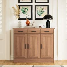 a wooden cabinet with three pictures on the wall above it