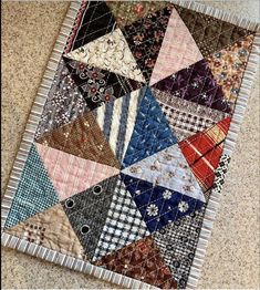 a patchwork quilt is laying on the floor with it's edges folded up