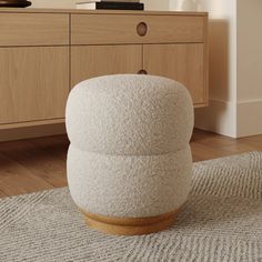 a white stool sitting on top of a wooden floor next to a dresser and drawers