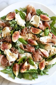 a white plate topped with salad covered in meat and veggies on top of a marble table