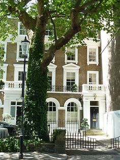 an apartment building with many windows and balconies on the front, next to a tree