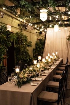 a long table is set up with candles and greenery for an elegant dinner party