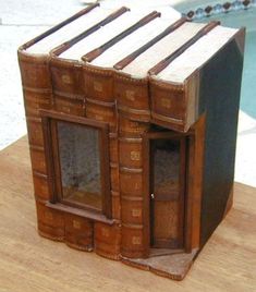 an old book like building made out of books on a wooden table next to a swimming pool