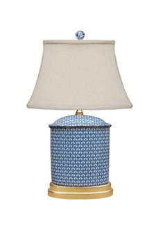 a blue and white table lamp with a light shade on the top, sitting against a white background