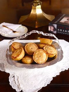 some pies are on a glass plate with a white doily next to a book