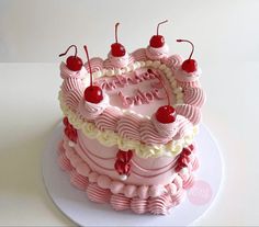 a pink birthday cake with cherries on top