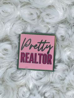 a pink pin with the words pretty realtor written in black on top of white yarn