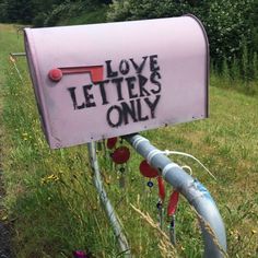 a mailbox with the words love letters only written on it in front of a grassy field