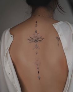 the back of a woman's neck with an arrow and flower tattoo on it