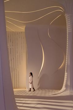 a woman walking through a room with white walls and lines on the wall behind her