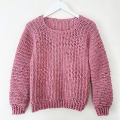 a pink sweater hanging on a white hanger