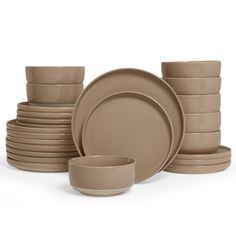 a stack of beige dinnerware with plates and cups next to each other on a white background