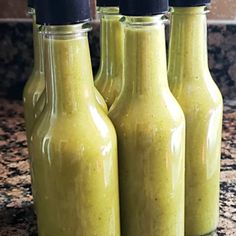 three bottles filled with green smoothie sitting on top of a counter next to each other