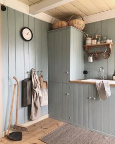 a kitchen with green painted walls and wooden flooring next to an oven, sink, and broom